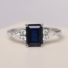 All HANDMADE ITEMS SHIP IN APPROX 8 DAYS Main Stone: Lab created sapphire Main Stone Size: Emerald cut 6 mm x 8 mm Main Stone Weight: 1.75 carat Side Stone: CZs Height From The Ring Setting Bottom(to gemstone top): about 5.13 mm Width of Ring band Measure: gradually varied,about 1.67 to 1.91 mm Material: .925 Sterling Silver/14K White Gold/14K Yellow Gold/14k Rose Gold Engraved: Available For FreeNo more than 13 letters) Customized:Of course! Tell me what you want Includes With Order: All of my Sapphire Engagement Ring Silver Band, Rectangular Sapphire Ring With Accent Stones, Rectangular Lab-created Sapphire Ring For Anniversary, Anniversary Rectangular Lab-created Sapphire Ring, Elegant Blue Sapphire Ring With Radiant Cut, Elegant Blue Radiant Cut Sapphire Ring, Blue Sapphire Ring In Emerald Cut Sterling Silver, Blue Emerald-cut Sapphire Ring In Sterling Silver, Rectangular Sapphire Anniversary Ring