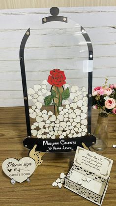 a glass vase filled with flowers on top of a wooden table next to two cards