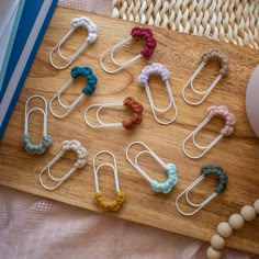 there are many different colored hair clips on the wooden board next to some balls and beads