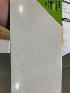 a white marble counter top with a green label on the front and back side, in a store