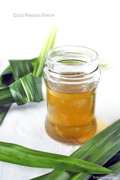 a jar filled with honey sitting on top of a table next to some green leaves