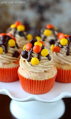 cupcakes decorated with candy and candies are on a white platter, ready to be eaten