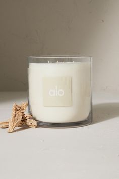 a white candle sitting on top of a table next to a piece of driftwood