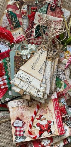 a pile of christmas tags on top of a piece of cloth with ribbons and bows