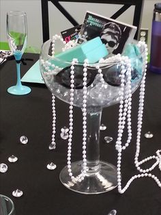 a table topped with a wine glass filled with glasses and pearls next to other items