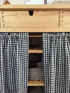 black and white checkered curtains are hanging on the side of a wooden bed frame