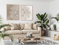 a living room filled with furniture and lots of plants in front of two paintings on the wall