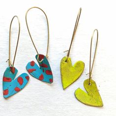 three pairs of colorful heart shaped earrings on white paper with gold earwires and hooks