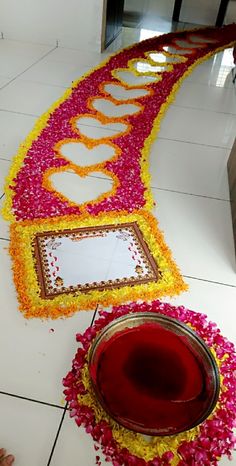 a long flowered path is decorated with mirrors and flowers on the floor in front of a door