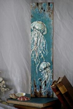 a wooden sign with an image of jellyfishs painted on it and seashells next to it