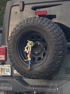 there is a toy man standing on the tire of a jeep