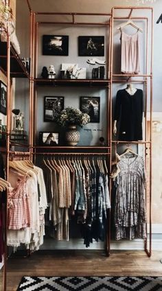 an open closet with clothes and pictures on the wall, hanging from metal shelving