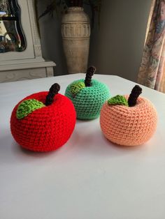 three crocheted apples sitting on top of a table