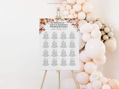 a wedding seating chart on a easel surrounded by balloons