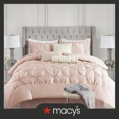 a bed with pink comforter and pillows on it