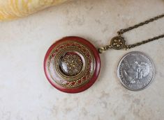 "Victorian style photo locket in a rich burgundy color has been layered with layers of bronze filigree detailed with intricate color inlaid in the filigree design on the locket. Each layer has been sealed with a clear resin so your locket will give you a lifetime of joy. Locket is 1 1/4\" in diameter and hangs from a bronze filigree connector with bronze plated chain. The chain fastens with a lobster clasp. Total pendant drop length including filigree connector is 2 1/4\" and is pictured with a Formal Red Medallion-shaped Jewelry, Victorian Red Medallion Jewelry, Red Victorian Medallion Jewelry, Bohemian Burgundy Jewelry Gift, Bohemian Burgundy Jewelry As Gift, Red Locket Necklace For Wedding, Mechanical Pocket Watch, Photo Locket Necklace, Rich Burgundy