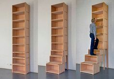 three wooden bookshelves in an empty room with one person standing on the stairs