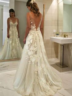 a woman standing in front of a mirror wearing a wedding dress with flowers on it