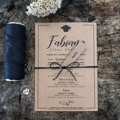 the wedding stationery is laid out on top of a piece of wood with a spool of thread next to it