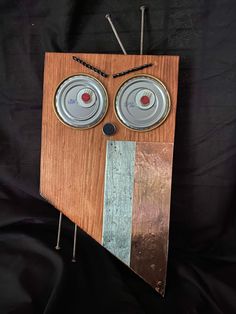 a piece of wood with some tin cans on it's face and two eyes