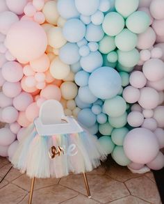 a baby's crib in front of a rainbow colored wall with balloons on it