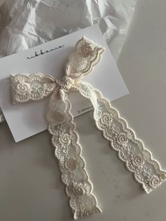 a white lace garter on top of a piece of paper next to a card