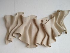 three pieces of wood carved to look like wavy lines on a wall, with one piece cut in half