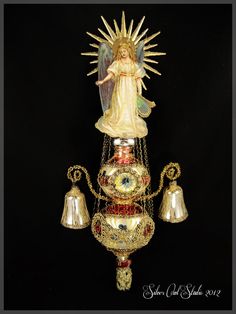 an angel figurine on top of a chandelier with bells and chains