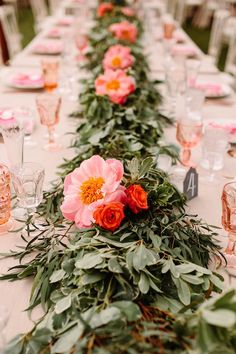 a long table with pink flowers and greenery