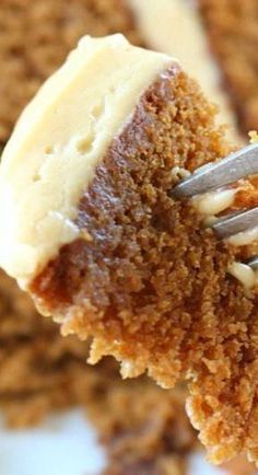 a piece of cake being held by a fork with white frosting on top and brown crumbs around the edges