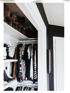 an open closet with clothes and shoes on the shelves, next to a white door