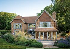 a large brick house with lots of windows and plants around it's front entrance