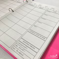 a pink binder sitting on top of a desk next to an open planner book