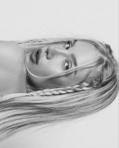 a black and white photo of a woman with long hair in braids looking at the camera