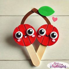 two red apples on a wooden stick with googly eyes and a green leaf sticking out of it