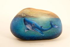 a painted rock with a blue whale on it