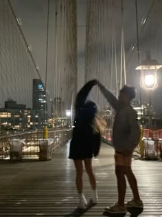 two people standing on a bridge at night