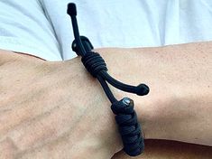 a man's arm wearing a black bracelet with silver beads