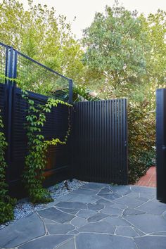 a black fence is surrounded by plants and rocks