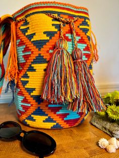 a multicolored woven bag with sunglasses on the floor