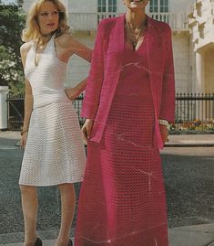 two women standing next to each other in front of a white building wearing dresses and jackets