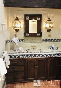 a bathroom with blue and white tiles on the counter top, wooden cabinets and mirror