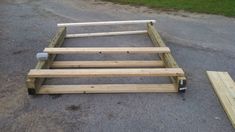 a wooden bed frame sitting on top of a gravel road