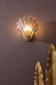 a wall light that is on the side of a wall next to a leaf shaped object