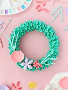 a wreath made out of cupcakes and seashells on a pink background