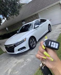 a white car parked in front of a house with a person holding the keys to it