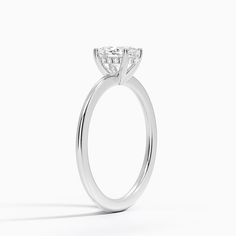 a white gold ring with a single diamond on the top and side stones at the bottom