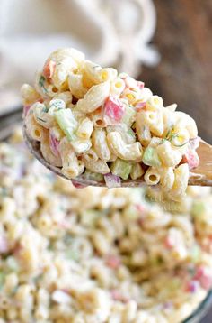 a spoon full of macaroni salad on top of a bowl