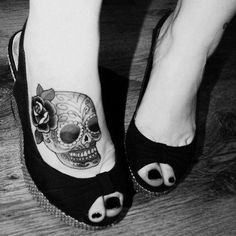 a woman's foot with a skull and rose tattoo on the side of her shoe