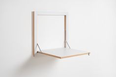 a white shelf mounted to the side of a wall with a wooden frame on it